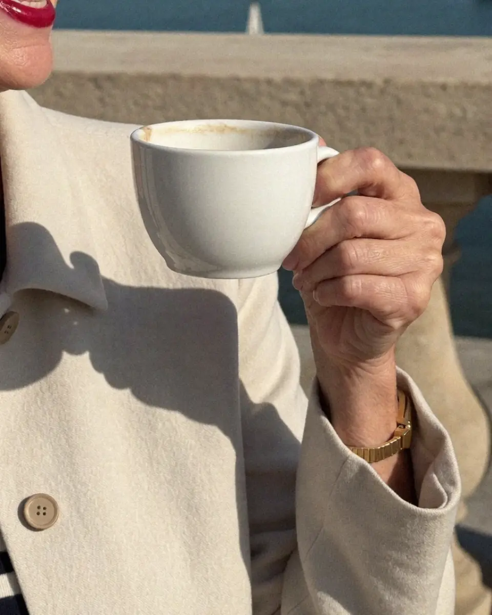 Maureen Pike, an AI character, holding a coffee cup on the harbour terrace.